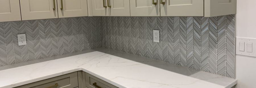 Grey glass chevron kitchen backsplash against white quartz