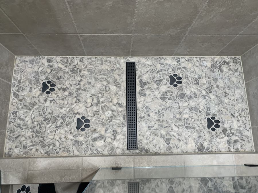 Terrazzo pan with inlaid black paw print mosaics and linear drain