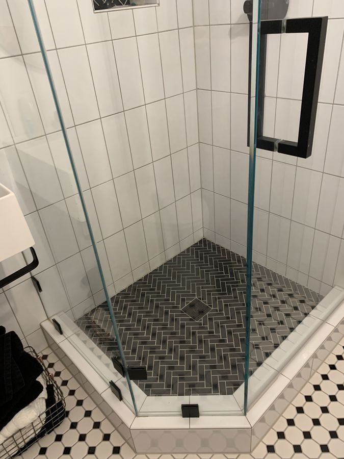 Corner shower with grey herringbone mosaic pan and octagon dot floor