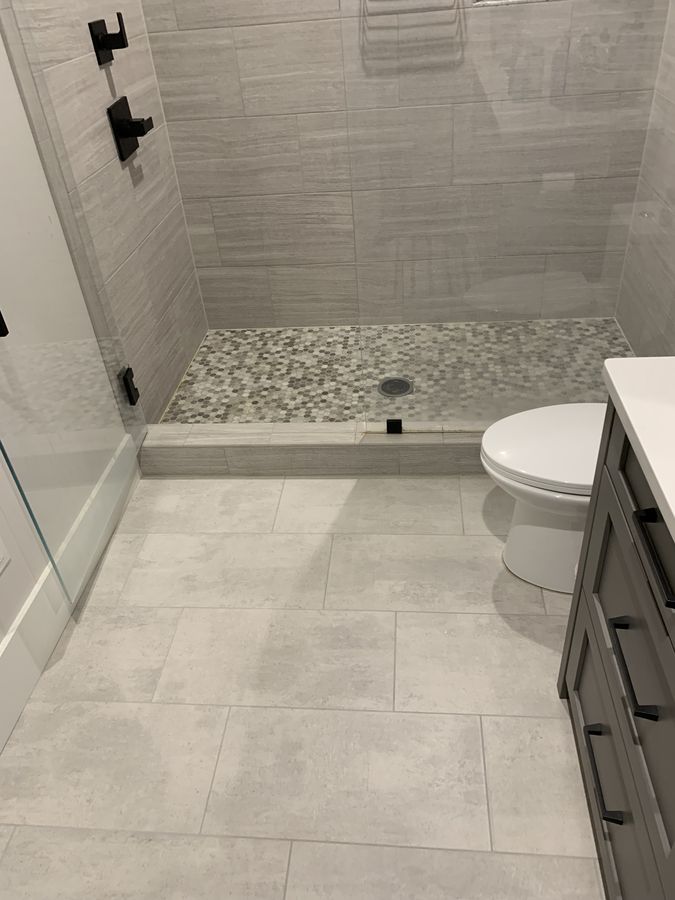 Bathroom floor running up to a tiled shower curb