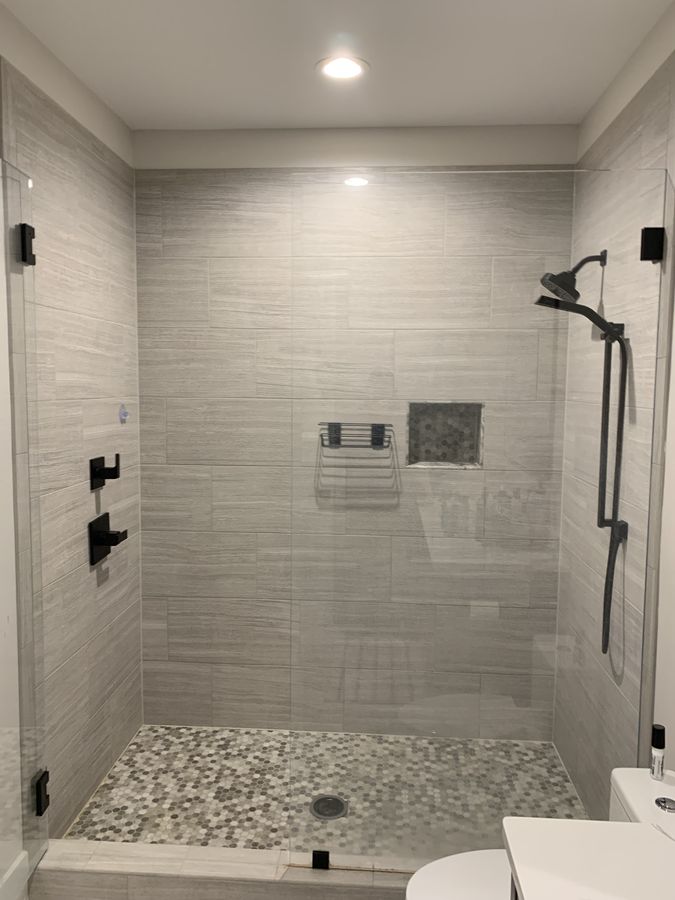 Grey linear texture tile shower with hex mosaic pan and niche