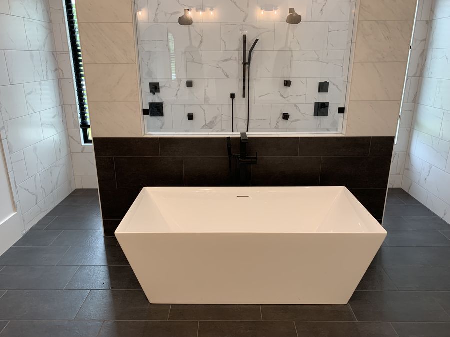 Freestanding tub against a dark tile accent band