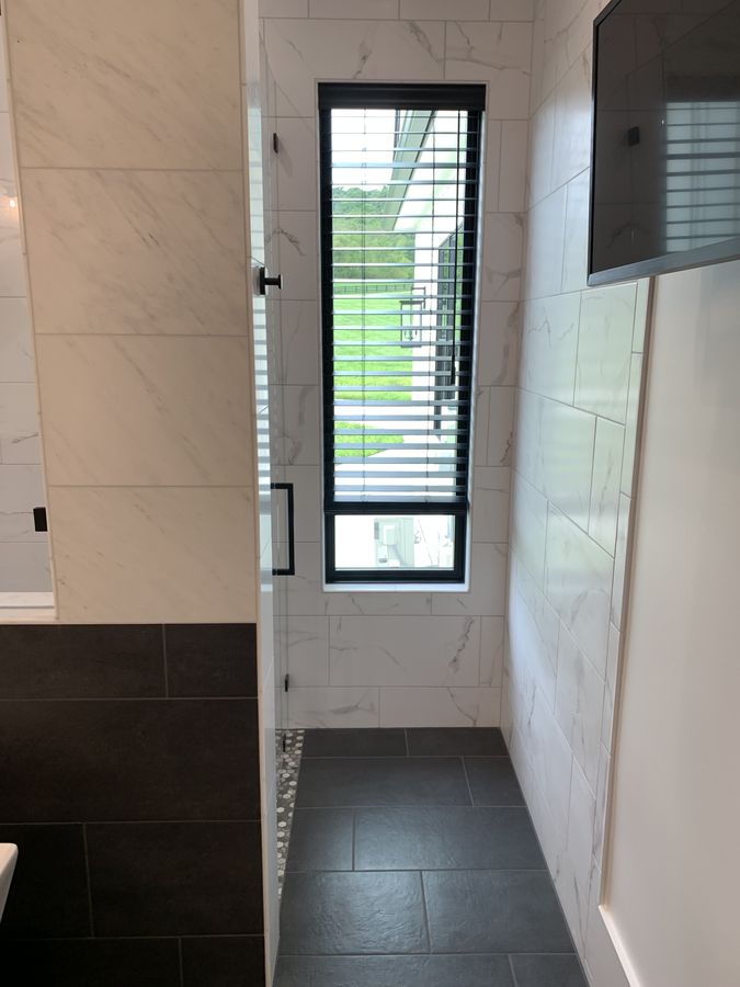 Walk-in shower with a window and slate look floor