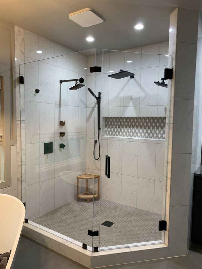 Large glass shower enclosure with marble look porcelain and arabesque band