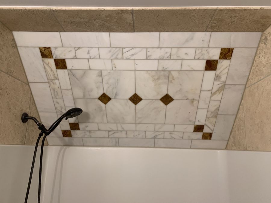 Tub alcove with marble and travertine decorative inset panel